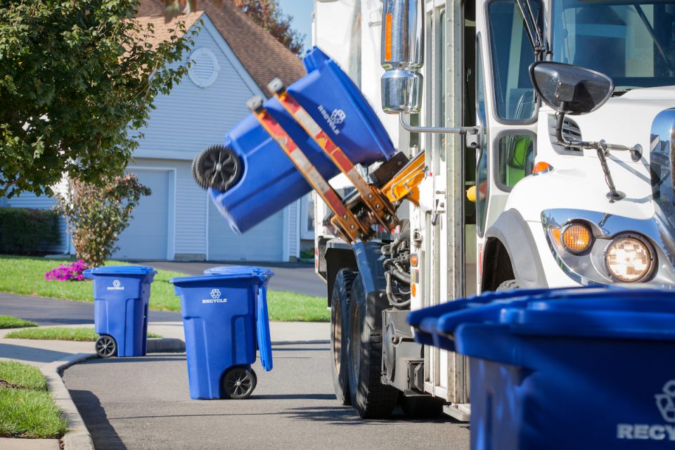 A truck picking up waste from recycling bins in a neighborhood.