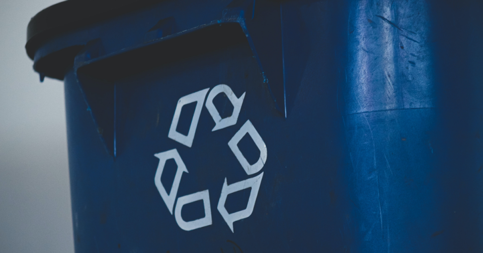 Recycling logo in white on a blue bin.